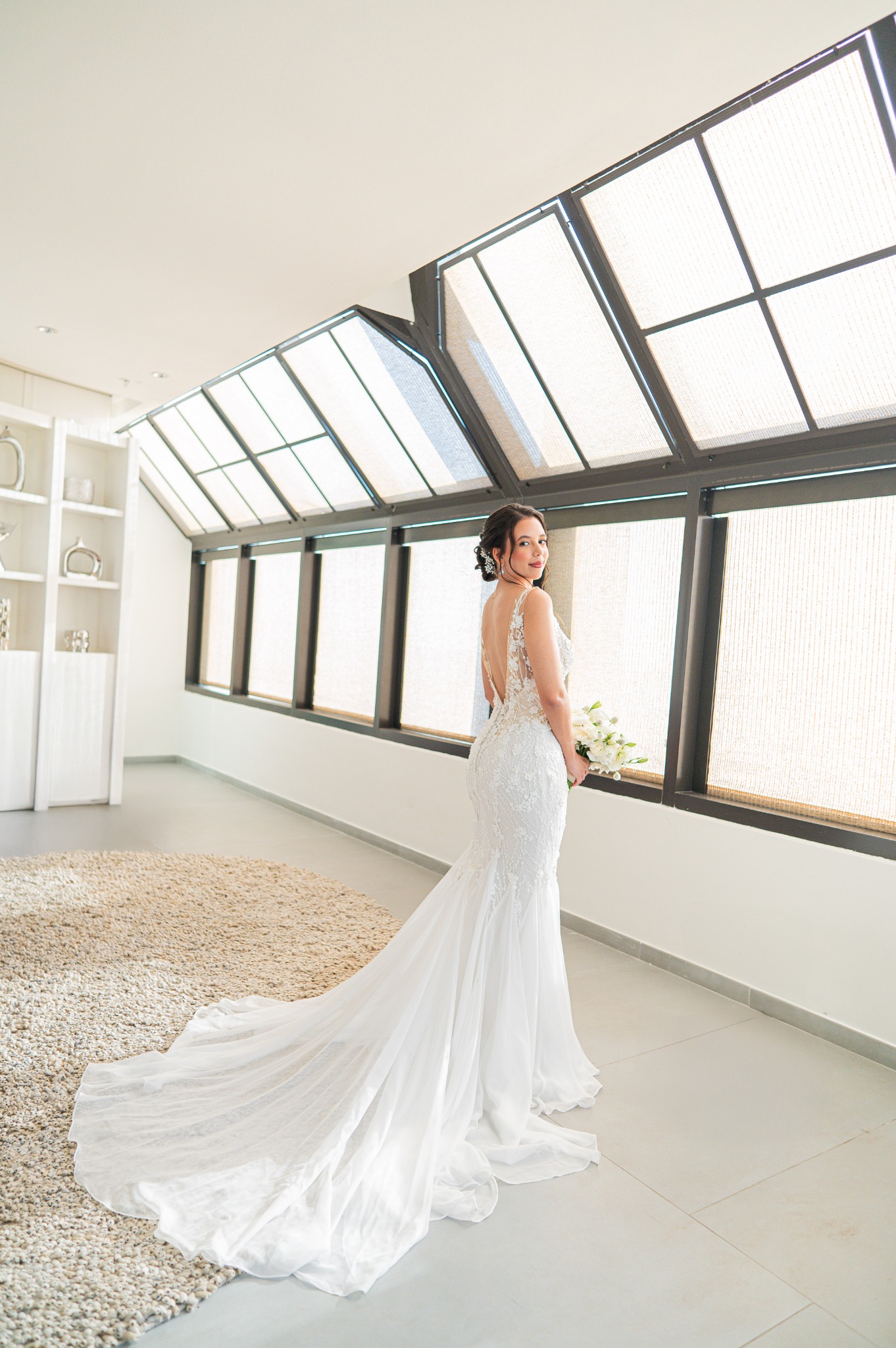 Bride showing her wedding gown in soft window light